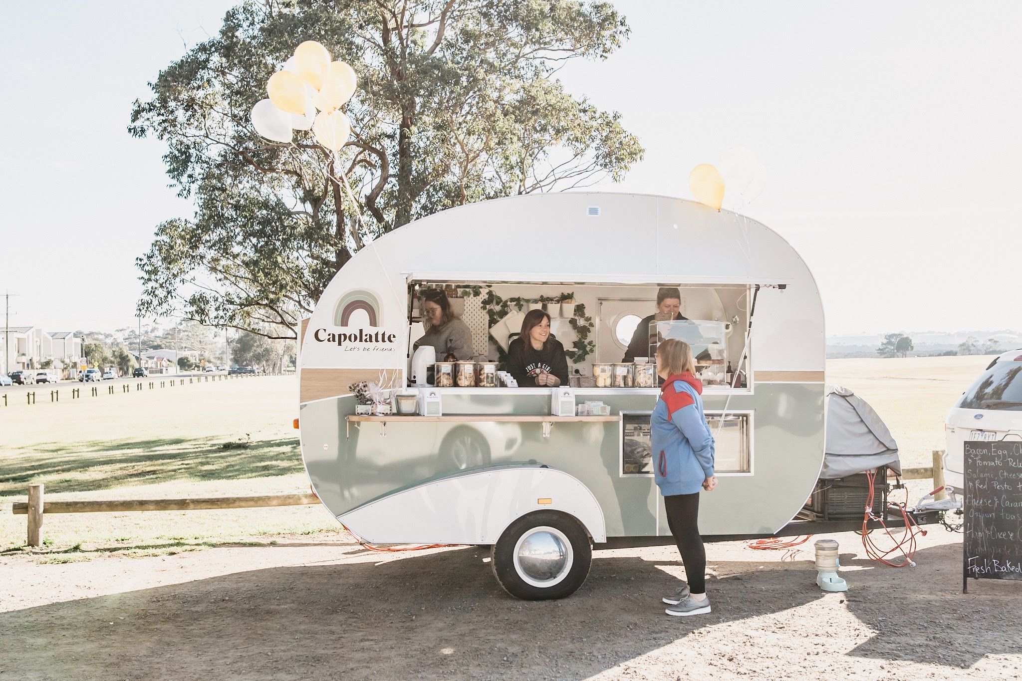 Capolatte coffee caravan at Hastings Foreshore with customer ordering and balloons on top