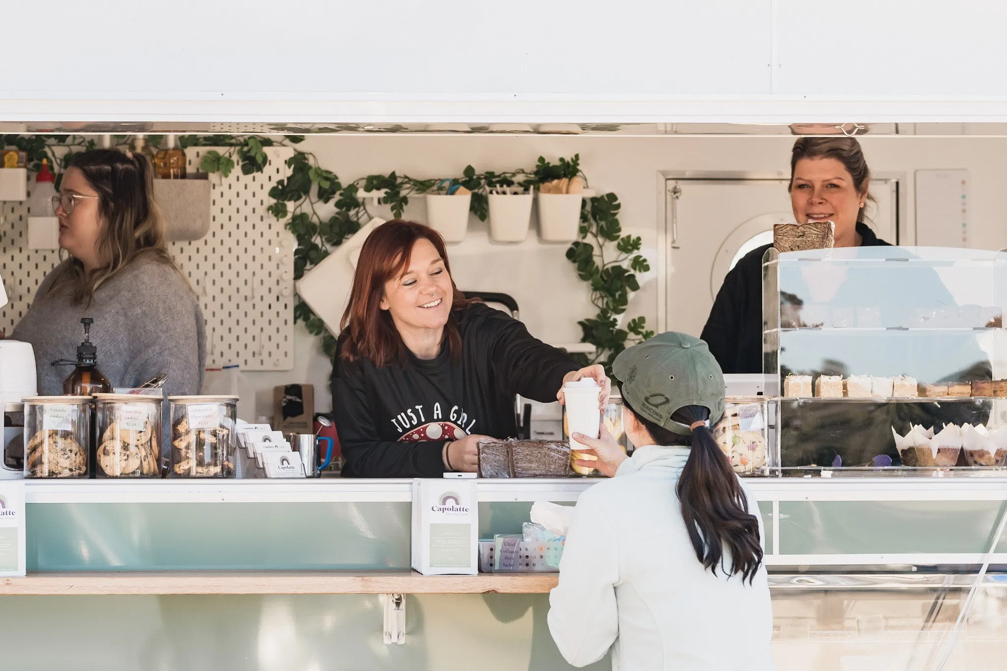 Capolatte barista smiling as she hands coffee to a customer at the van window