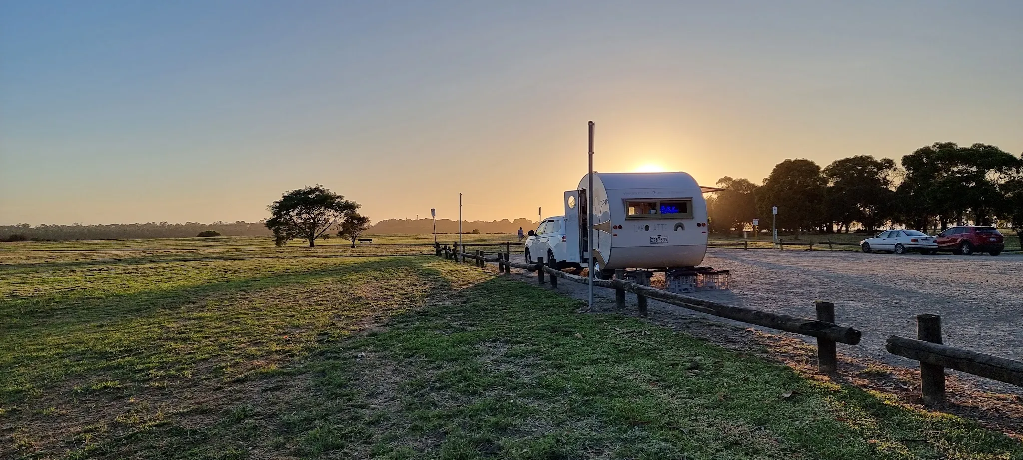 Capolatte coffee caravan at the foreshore at sunset with glowing interior lights