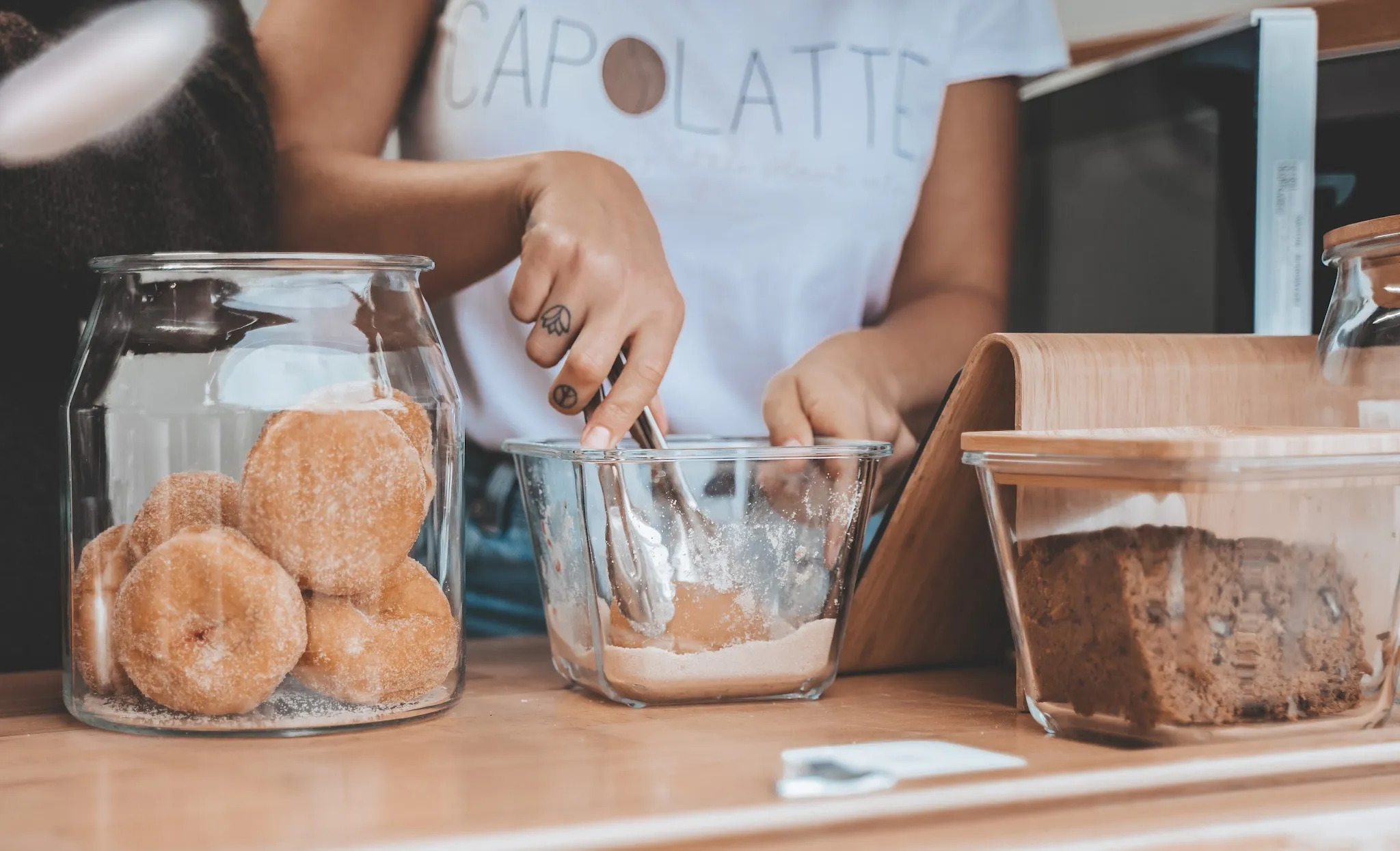 Capolatte staff hands preparing cinnamon sugar donuts at the counter